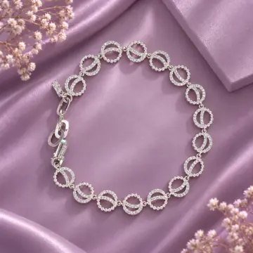 Women's silver link bracelet arranged in a circle on purple satin